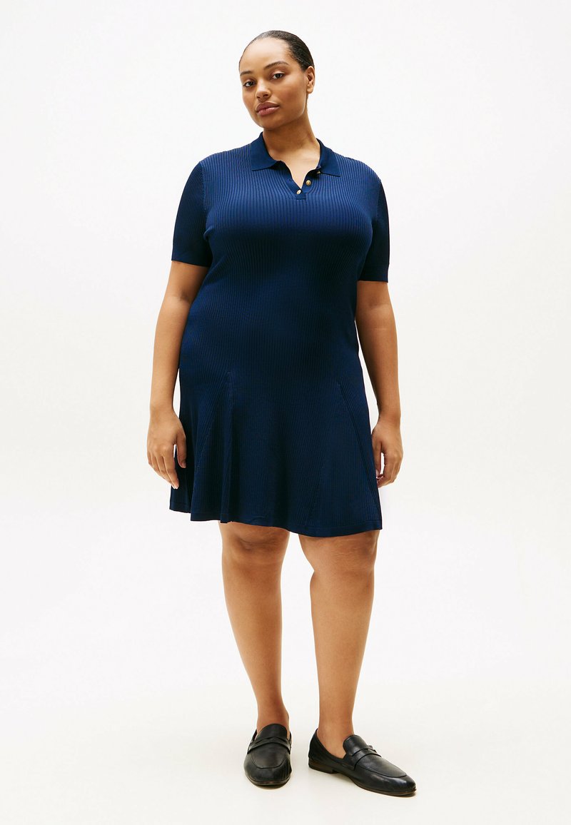 Navyblaues, geripptes Kleid mit Polokragen, kurzen Ärmeln und ausgestellt geschnittenem Saum. Verfügt über drei dekorative Knöpfe am Ausschnitt.