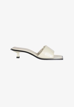 Mule beige con punta aperta, tacco kitten basso e ampia fascia imbottita, con punta quadrata e bordo suola nero.