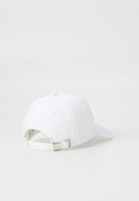 Witte katoenen baseballcap met een ronde kroon, verstelbare band aan de achterkant en een kleine metalen sluiting. Vriendelijke textuur zonder patronen.
