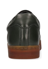 Bakvy av mörkgröna lädersneakers med synlig söm och tjock, genomskinlig brun gummisula på vit bakgrund.