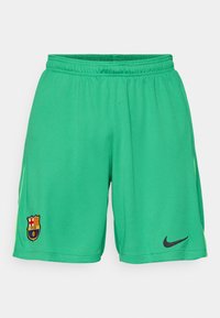 Grønne fodboldshorts lavet af struktureret stof, med et sort Nike-logo og et Barcelona klubmærke på venstre ben.