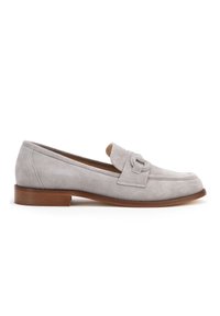 Mocassino in suede grigio chiaro con suola piatta marrone, caratterizzato da una striscia decorativa sulla parte superiore e un design a punta arrotondata.