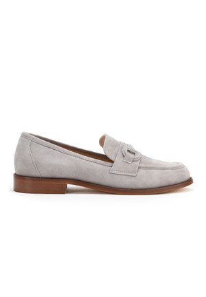 Mocasines de ante gris claro con suela plana marrón, que presentan una tira decorativa en la parte superior y un diseño de punta redondeada.
