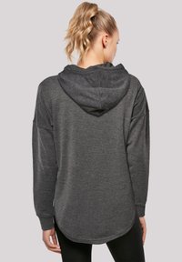 Mørk grå hettegenser med avslappet passform, teksturert stoff, lange ermer og rundet nederkant. Minimalistisk design uten synlige logoer.