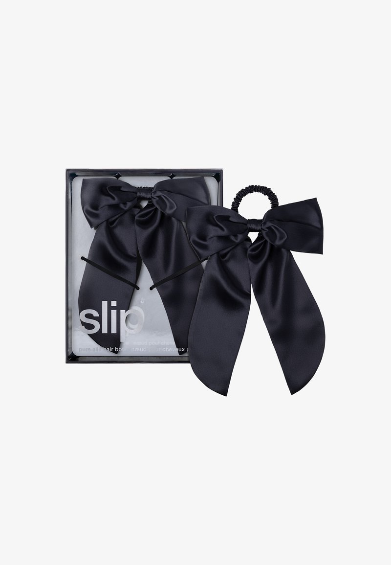 Accesorios de cabello de seda negra en una caja, que incluyen dos lazos grandes y una banda elástica. Textura suave con un acabado brillante.
