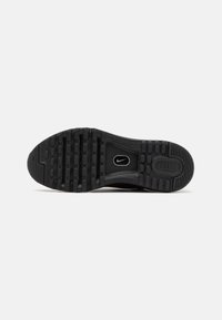 Sole preta da Nike Air com borracha texturizada, apresentando botões arredondados para aderência e uma seção central lisa com detalhes do logótipo.