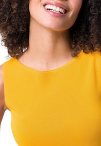 Haut sans manches jaune vif avec une texture côtelée lisse et un col arrondi. Focus sur le haut du corps et la zone du col.