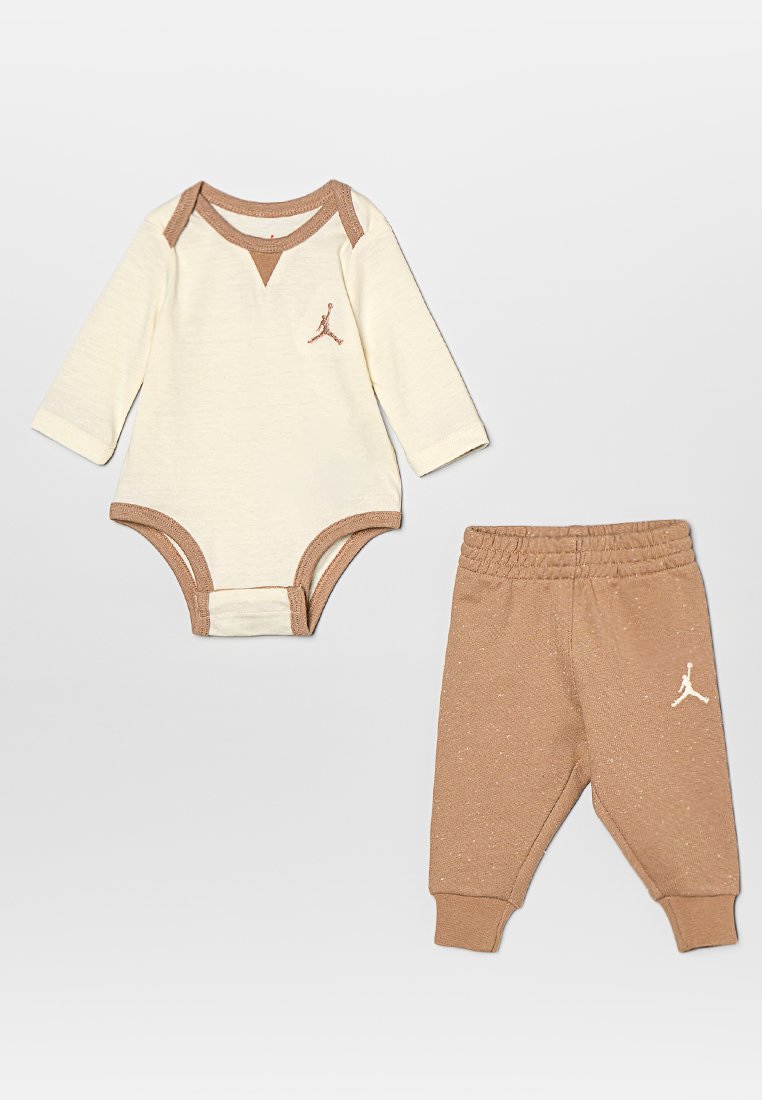 Bodysuit de crema clara con ribetes marrones y logo; pantalones de chándal marrones a juego con cintura elástica y logo. Tejido suave de mezcla de algodón.