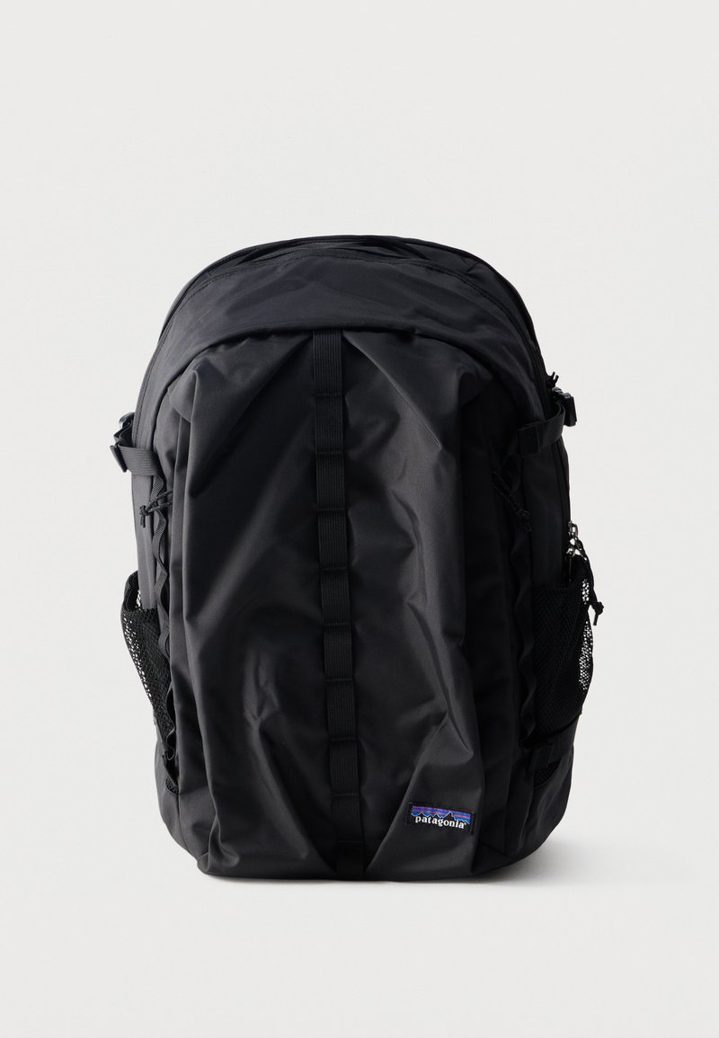 Μαύρο σακίδιο πλάτης Patagonia με κάθετο ιμάντα μπροστά, δίχτυ πλαϊνές τσέπες και επάνω διαμέρισμα με φερμουάρ σε απλό λευκό φόντο.
