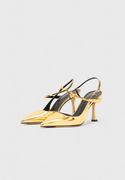 Talons aiguilles dorés métalliques avec un bout pointu et une silhouette élégante. Comprend une fine bride de cheville et un design de talon aiguille.