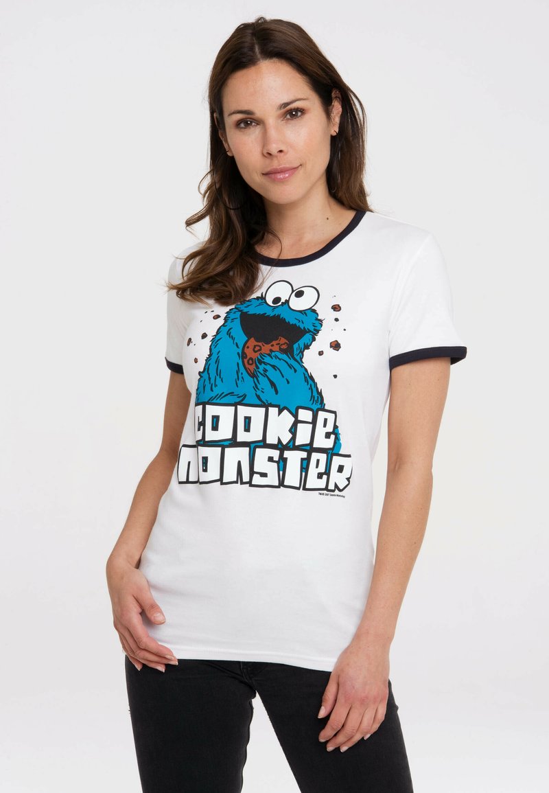 White t-shirt with navy trim featuring a bold blue Cookie Monster graphic holding a cookie. Text reads "COOKIE MONSTER" in large black letters.