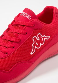 Rode sportieve schoen van mesh en suede materialen, met dikke veters, een gevoerde kraag en een wit geborduurd logo aan de zijkant.