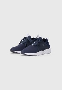 Pair of navy blue sneakers with white soles and dotted laces, displayed on a light gray background.