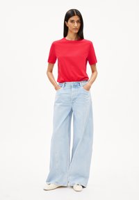 Rode korte mouwen T-shirt met een ronde hals, gecombineerd met lichtblauwe wijde jeans met hoge taille en zijzakken.