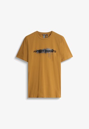 Senfgelbes Baumwoll-T-Shirt mit kurzen Ärmeln, das einen grafischen Druck von "ANTONY MORATO" in schwarzer und grauer Tinte mit Tropfeneffekten zeigt.