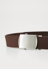 Brown woven fabric belt with a rectangular matte silver metal buckle against a plain white background.