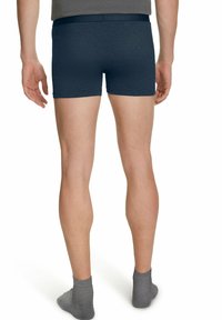 Boxer da uomo blu navy con una cintura morbida, abbinati a calzini grigi alla caviglia. Il tessuto appare liscio con una sottile texture.