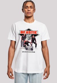 White t-shirt featuring a graphic print of three figures with a boombox. Text reads "BEASTIE BOYS" in bold red and black. Casual fit.