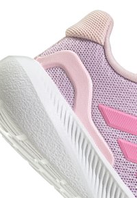 Zapatilla deportiva de malla púrpura con una suela de goma blanca texturizada. Presenta detalles en rosa y un collar acolchado para mayor comodidad.