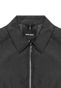 Giubbotto nero con colletto classico, zip intera e fodera in rete interna. Presenta un'etichetta cucita all'interno con il nome del marchio.