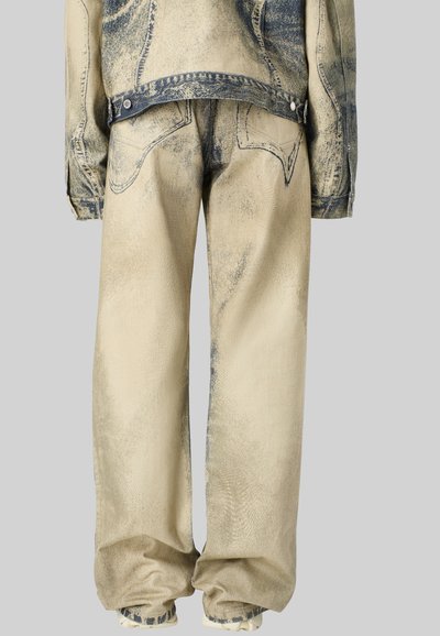 Denimjakke og -bukser i beige med blå accenter, der har en tekstureret finish, oversized pasform og synlige syninger på lommerne.