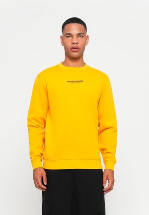 Geel sweatshirt met lange mouwen en een ronde hals. Versierd met "WEEKEND OFFENDER" en "ADMIT NOTHING" in zwarte tekst.