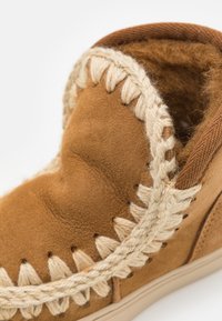 Bottines en daim marron avec un accent tressé couleur crème le long du bord, doublure en fourrure douce et design à bout rond.