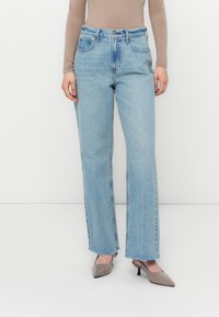 Lysvaskede denimjeans med høyt liv, rett benpassform, frayskant, og fem lommer, kombinert med grå spisse hæler.