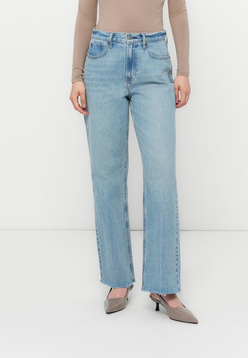 Lysvaskede denimjeans med høyt liv, rett benpassform, frayskant, og fem lommer, kombinert med grå spisse hæler.