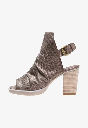 Chaussure ouverte en bronze métallique avec une texture plissée, bride de cheville et un talon bloc présentant un motif rayé ressemblant à du bois.