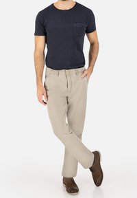 Navy short-sleeve t-shirt with a chest pocket, paired with light beige straight-leg pants and brown lace-up shoes.