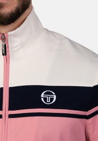 Reißverschlussjacke mit hohem Kragen, aus strukturiertem Stoff mit weißen, marineblauen und rosa horizontalen Streifen; Logo auf der Brust.