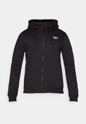 Sort zip-up hoodie lavet af blødt stof, med en hætte med snøre og ribbede manchetter. Bemærkelsesværdig Reebok-logo på venstre brystområde.