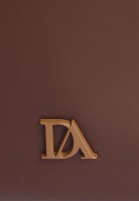 Superficie de cuero marrón con un acabado texturizado y un logotipo en tono marrón claro destacado, que combina las letras "D" y "A" en un diseño moderno.