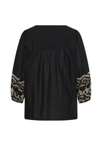 Blouse noire à manches longues avec broderie florale beige sur les poignets, coupe ample, tissu froncé sous le décolleté carré, vue de dos.