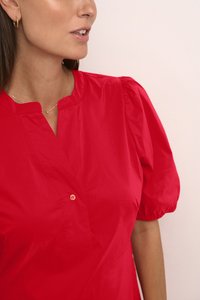 Bluză roșie cu mâneci bufante și decolteu cu tăietură, având un singur nasture și o textură fină. Materialul pare ușor și lucios.