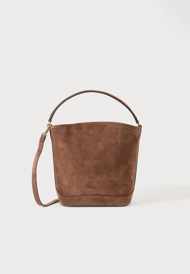Sac seau en daim marron avec un dessus arrondi, une anse courte unique et une longue bandoulière amovible sur un fond uni.