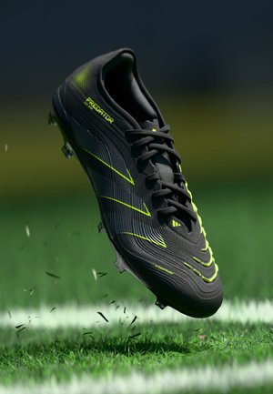 Black soccer cleat with green accents, textured upper, and distinctive curved lines; features visible studs for traction on grass.