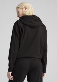 Schwarzer Hoodie mit gerippter Textur, ausgestattet mit einer Kapuze mit Kordelzug, entspannter Passform und Bündchenärmel, kombiniert mit passenden Hosen.