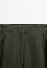 Vihreät oliiviharmaat housut on valmistettu teksturoituneesta kankaasta, niissä on suora vyötärönauha, jossa on laskokset, sekä kaksi sivutaskua käytännölliseen tyyliin.