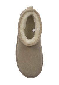 Brązowe zamszowe klapki z miękkim, białym sztucznym futerkiem w środku. Zaokrąglony kształt z teksturowanym wykończeniem i pętelką z tyłu ułatwiającą zakładanie.