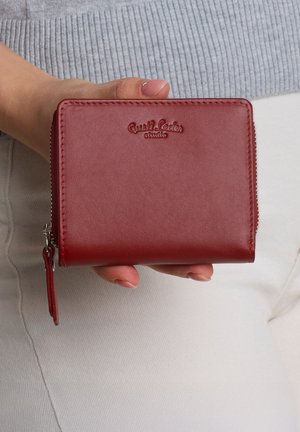 Red leather wallet with embossed logo, zip closure, and sleek rectangular design. Features a wrist strap and smooth texture.
