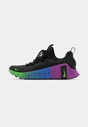 Zapatilla deportiva negra con parte superior texturizada, entresuela degradada en verde, azul y púrpura, y un logotipo de Nike verde en la punta.