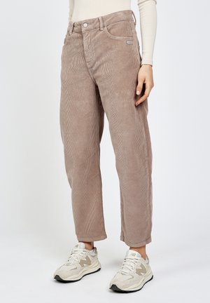 Taupe straight-leg corduroy pants worn with cream long-sleeve top and white New Balance sneakers on light background.