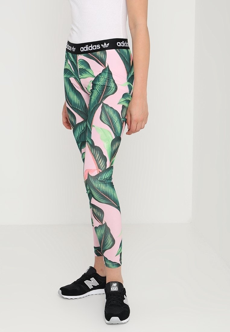 Legíny Adidas s černým páskem, s růžovým pozadím zdobeným velkými zelenými listovými vzory. Ušitý design, vhodné pro aktivní nošení.