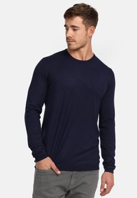 Camisa de manga larga azul marino hecha de tela acanalada, con escote redondo, diseño ajustado y acabado ligeramente texturizado.