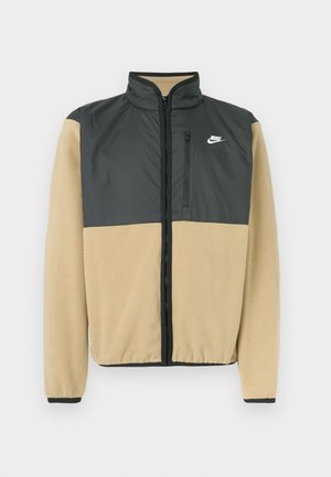 Nike fliisjakki, millel on jagatud disain tumehall ülaosa ja beež alaosa, lukuga tasku ja kõrge krae.