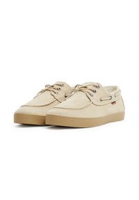 Scarpe da barca in tela beige con punta rotonda, lacci, occhielli in metallo e suola in gomma texturizzata. Accentuate da una piccola etichetta del marchio.