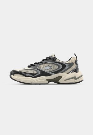 Black and cream athletic shoe with a mesh upper, textured details, thick sole, and prominent lacing system. Features the Lacoste logo.