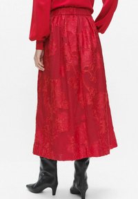 Red floral-patterned midi skirt with an elastic waist, crafted from lightweight fabric, featuring a flowy design and a hem that falls below the knee.